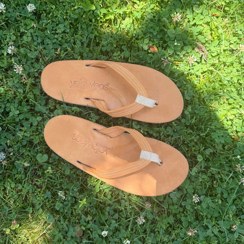 Pair of handmade tan leather sandals on a grassy background